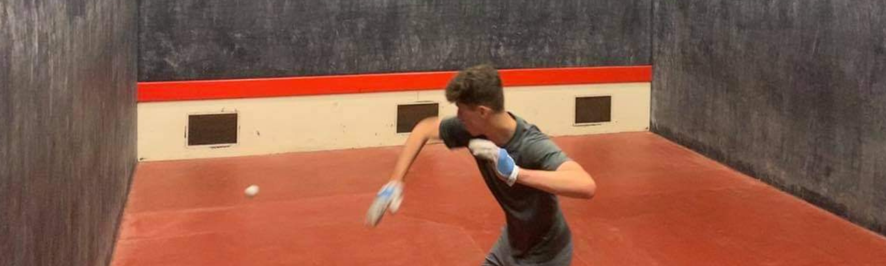 One player on a rugby fives court preparing to hit a ball